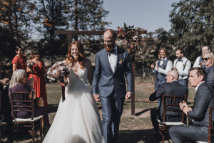 Newlyweds holding hands and walking down the aisle.